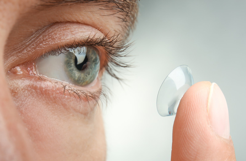 A woman placing a contact lens on her left eye