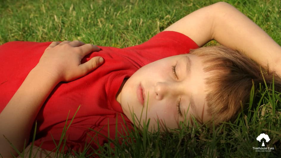 Young boy in a red shirt lying on green grass